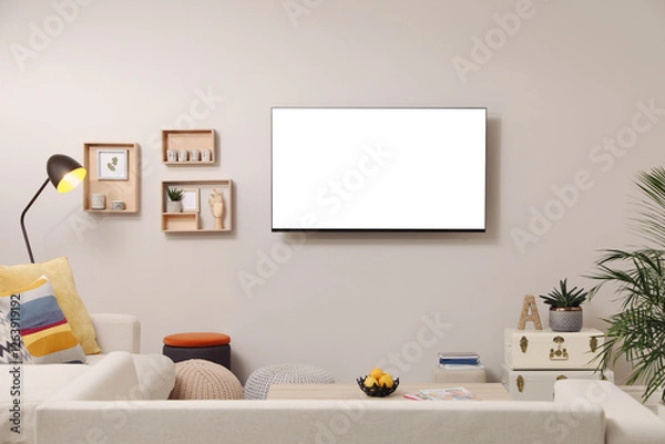Fototapeta Tv set with white screen mounted on wall in room. Mockup for design