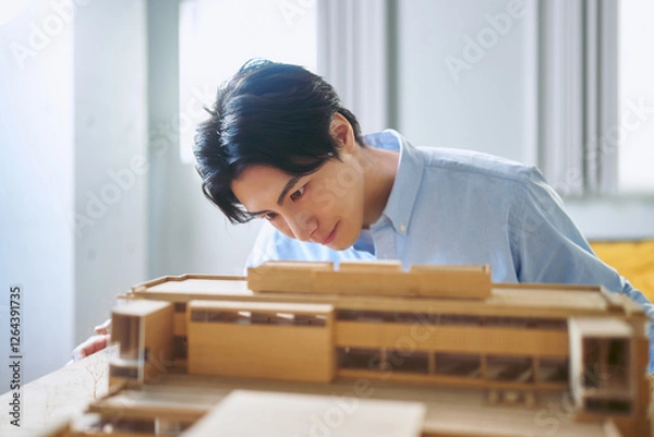 Obraz 工学部のある大学で真剣な表情で建築模型を作る1人の男性の建築学科の学生