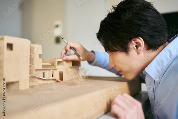 Obraz 設計のコンペディションの為の建築模型を真剣に想像力を働かせて作る1人の男性