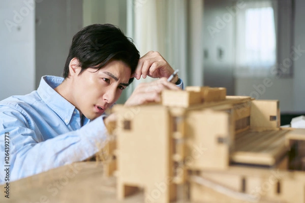 Obraz 仕事場で建物の模型を見て建築物の構想をする技術者