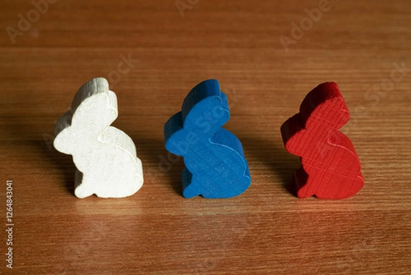 Fototapeta Three wooden colorful rabbit figures one after the other on a wooden table close-up