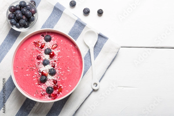 Fototapeta Strawberry and beetroot smoothie bowls topped with blueberries, pomegranate, chia seeds and shredded coconut. Top view and copy space