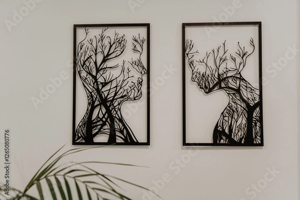 Fototapeta Modern black metal wall art featuring two framed abstract silhouettes of human faces intertwined with tree branches, mounted on a white wall in a contemporary interior with a minimalist aesthetic