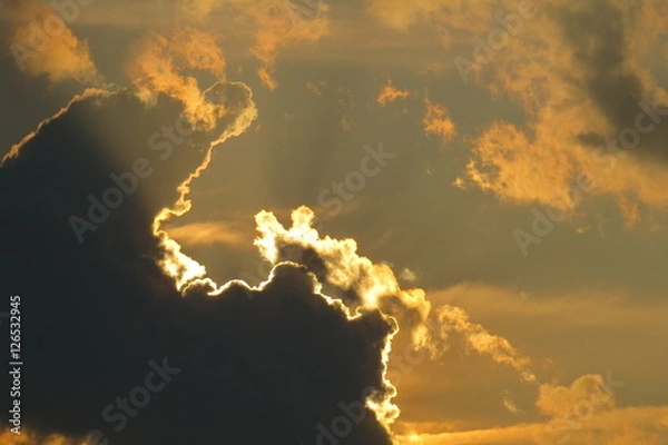 Obraz Bright rays of light passing near dark clouds.