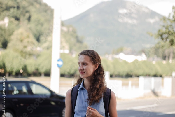 Obraz A young girl with a backpack walks down the street with a backpack. The student looks away.
