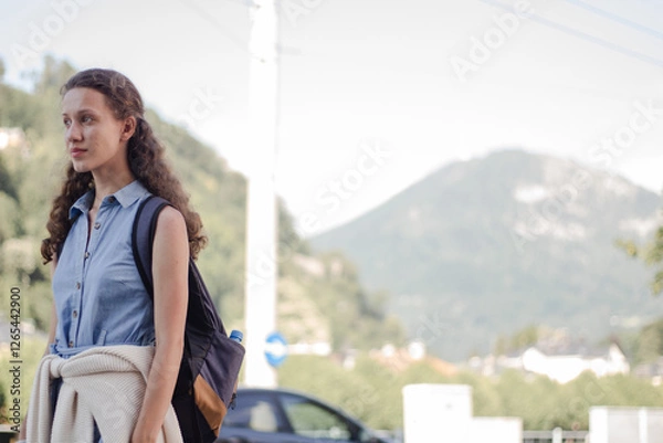 Obraz A young girl with a backpack walks down the street with a backpack. The student looks away.