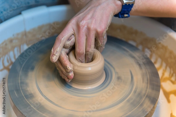 Fototapeta womens hands of a potter creating an earthen jar