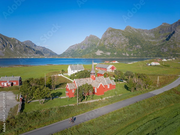 Fototapeta Aerial view overlooking Flakstad Church in Flakstad. In the background, among other things, the peaks of the mountains Blekktinden and Digertinden. Lofoten District in Norway