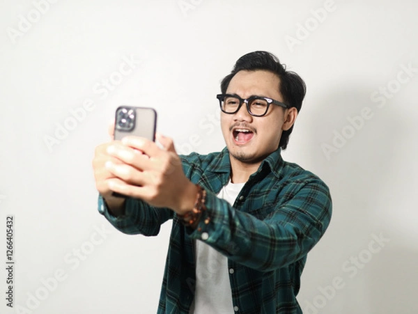 Obraz Adult Asian man typing on his mobile phone with excited expression isolated on white background