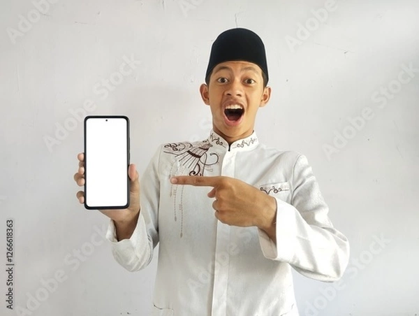 Fototapeta Asian Muslim man points to blank smartphone screen with shocked expression 