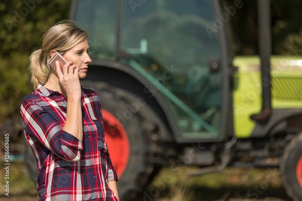 Fototapeta female farmer with tractor using mobile phone