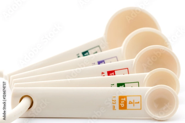 Fototapeta measuring spoons in varying sizes on white background