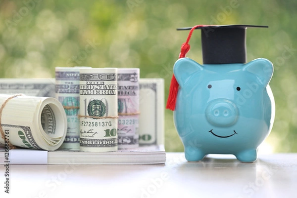 Fototapeta Graduation hat on piggy bank with stack of coins money on natural green background, Saving money for education concept