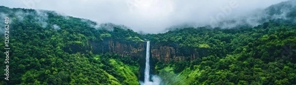 Fototapeta Majestic Waterfall Cascading Down Lush Green Mountains Surrounded by Mist and Dense Forest in Nature