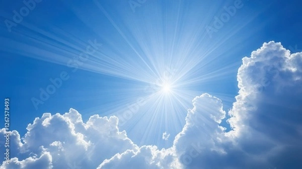Fototapeta Bright sunbeams through clouds in a clear blue sky