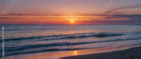 Fototapeta Sunset over calm ocean waves with reflection on sandy beach and colorful sky in the background Copy Space