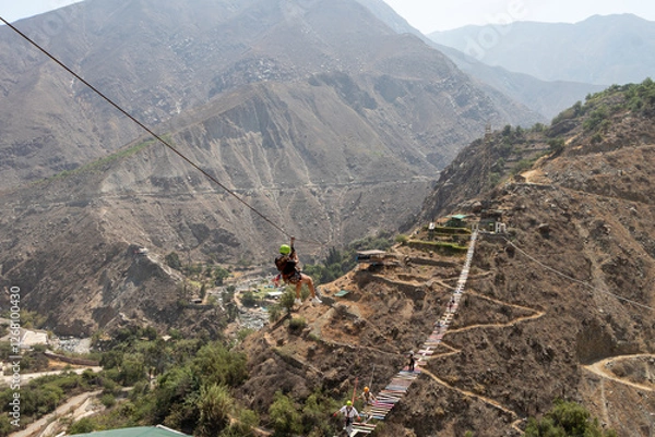 Fototapeta mujer haciendo deporte extremo canopy en la montaña con accesorios de seguridad y casco color verde