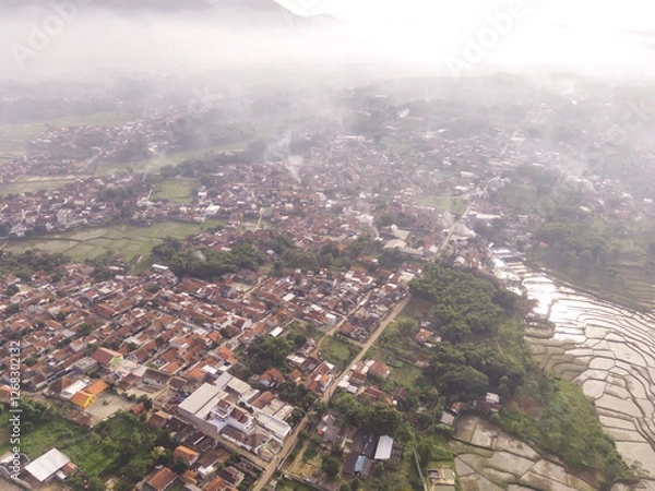 Fototapeta Aerial view of a residential neighborhood showcasing houses, roads, and trees on Foggy Morning. Fog covering residential District in the countryside. Drone Photography concepts. Negative Space