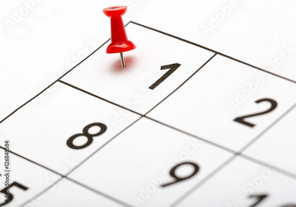Fototapeta Pin on the date. The first day of the month is marked with a red thumbtack. Focus point on the red pin.