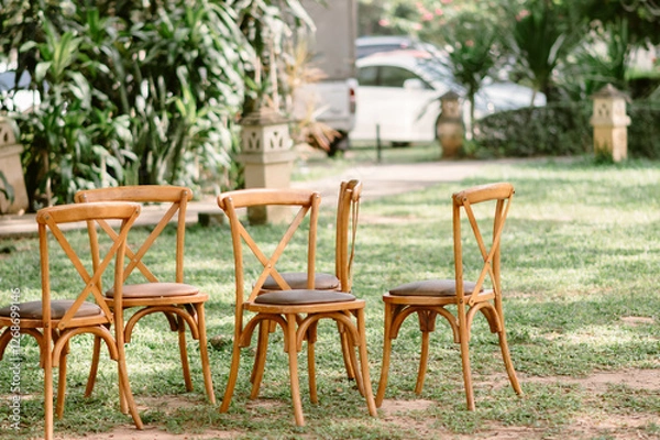 Fototapeta Five brown wooden chairs are placed on the grass in the garden