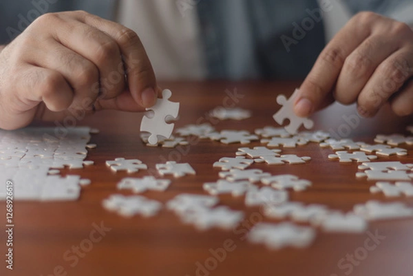 Obraz A man's hand is putting together a jigsaw puzzle.