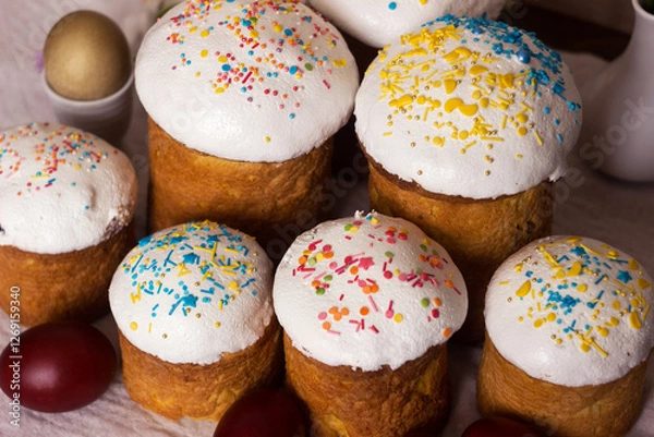 Obraz Easter bread with icing and colourful sprinkles on a table with Easter eggs, Food for Easter.