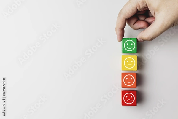 Fototapeta Hand placing green wooden blocks with emoticon faces feel happy according to color scale. Concept of satisfaction rating, customer evaluation, and satisfaction survey. with copy space