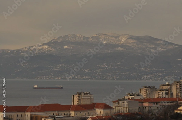 Fototapeta Rijeka city panoramic wiev of Kvarner gulf, ship entering in harbour and in background Ucka mountain covered with snow