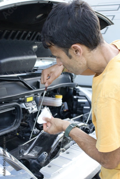 Fototapeta Mechanic checking motor oil level in camper van engine.