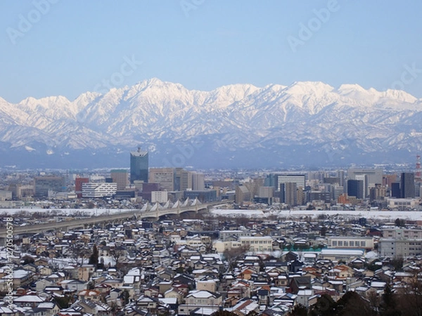 Fototapeta 冠雪の北アルプス剱立山連峰と雪化粧の富山市街地