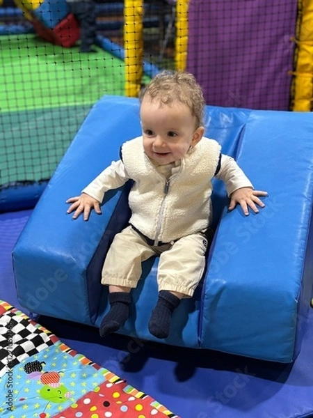 Fototapeta A baby boy playing and having fun in a soft play centre