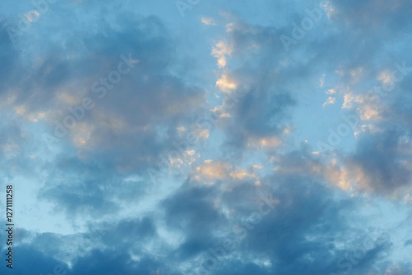 Fototapeta Grey fluffy clouds with sunlit highlights, against a blue sky