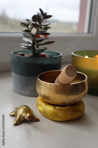 Fototapeta Flower pot, singing bowl and golden turtle on the window sill, close up.