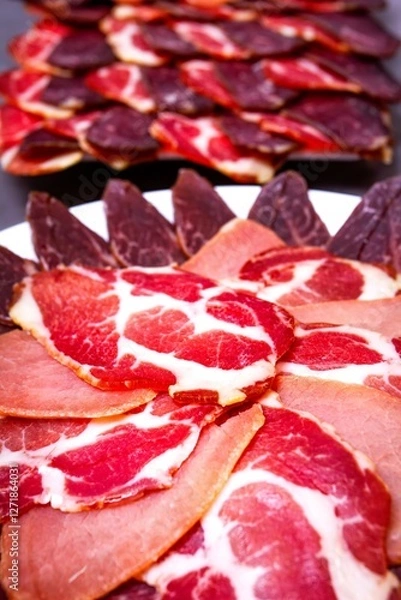 Fototapeta Sliced meat on a plate on a gray background