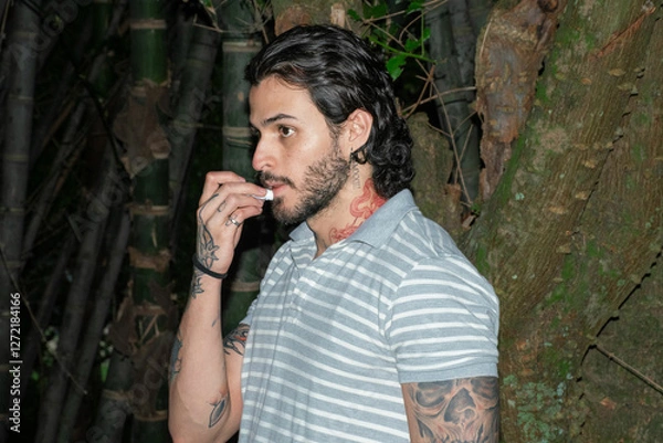 Obraz Young tattooed man using lipbalm