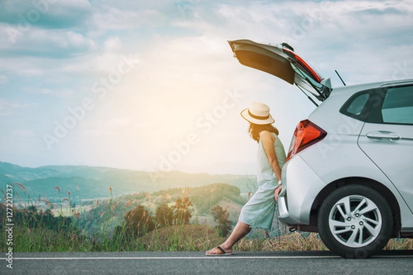 Obraz Kobieta podróżnik siedzi na samochodzie typu hatchback z górskim tłem w tonie vintage