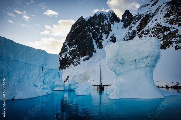 Fototapeta Antarctic Peninsula: Snowy peaks, icebergs, cloudy sky. Lemaire Channel