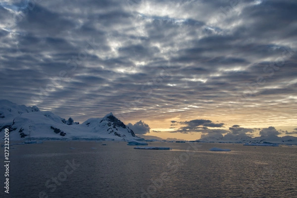 Fototapeta Antarctic Peninsula: Snowy peaks, icebergs, cloudy sky. Lemaire Channel