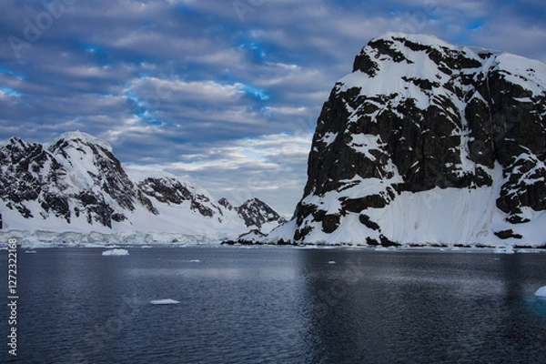 Fototapeta Antarctic Peninsula: Snowy peaks, icebergs, cloudy sky. Lemaire Channel