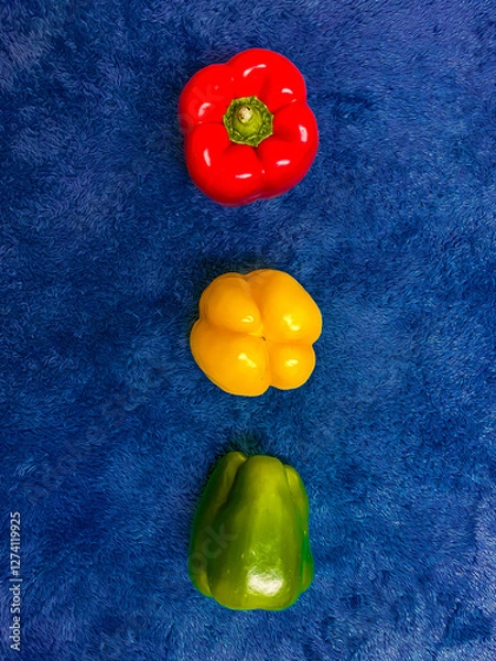 Fototapeta The colored peppers are arranged like the colors of a traffic light on a blue background