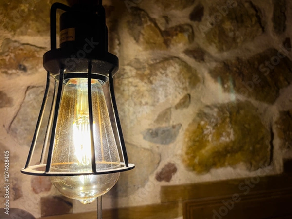Fototapeta Rustic Hanging Lamp Illuminating a Textured Stone Wall..