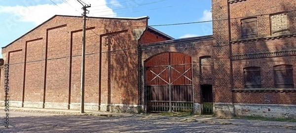 Fototapeta An old brick building with many windows covered with wooden shutters Sovetsk 2024 July 17
