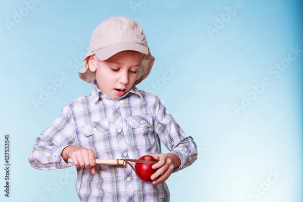 Obraz Young boy use sling shot hold apple.