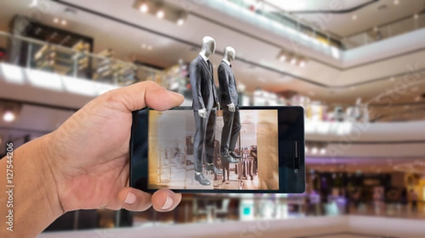 Obraz Augmented reality application for retail business concept. Hand holding smart phone with A/R application on screen to finding shop in department stroe.