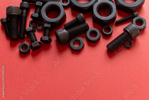 Fototapeta 赤背景に並ぶ複数の六角ナットとボルト	