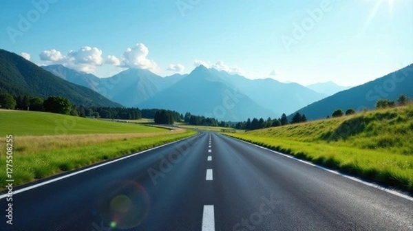 Fototapeta Asphalt ribbon unwinding towards a majestic mountain range under a serene summer sky, promising adventure and scenic exploration
