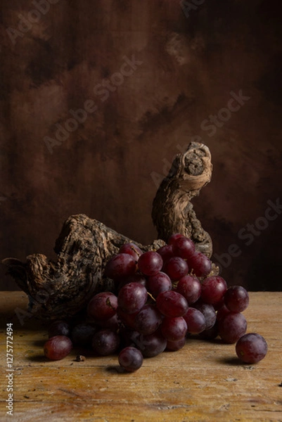 Fototapeta View of bunch of red grapes on vine trunk, dark background, vertical with copy space