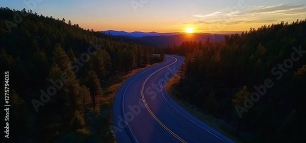 Fototapeta Winding Road Through Forest at Sunset with Mountains in the Background
