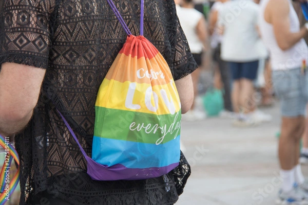 Obraz person taking on his back a lgbt pride and reusable bag in the city. rainbow. Horizontal