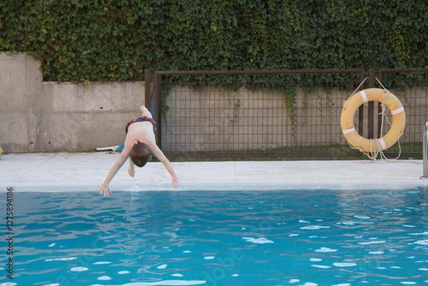Obraz boy jumping and diving headfirst into the pool, swimming, horizontal, copy space, summer